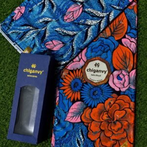 Vibrant floral Ankara fabric with blue, pink, orange and black colors, accompanied by a matching box on green grass.