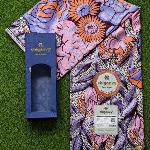 A vibrant floral patterned fabric and a blue box on a grassy background, perfect for traditional African attire.