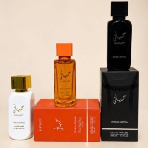 Three luxury perfume bottles in white, orange and black with gold accents, arranged on and next to their respective boxes.